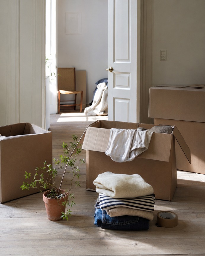 Open moving boxes with folded clothes, seen through a doorway